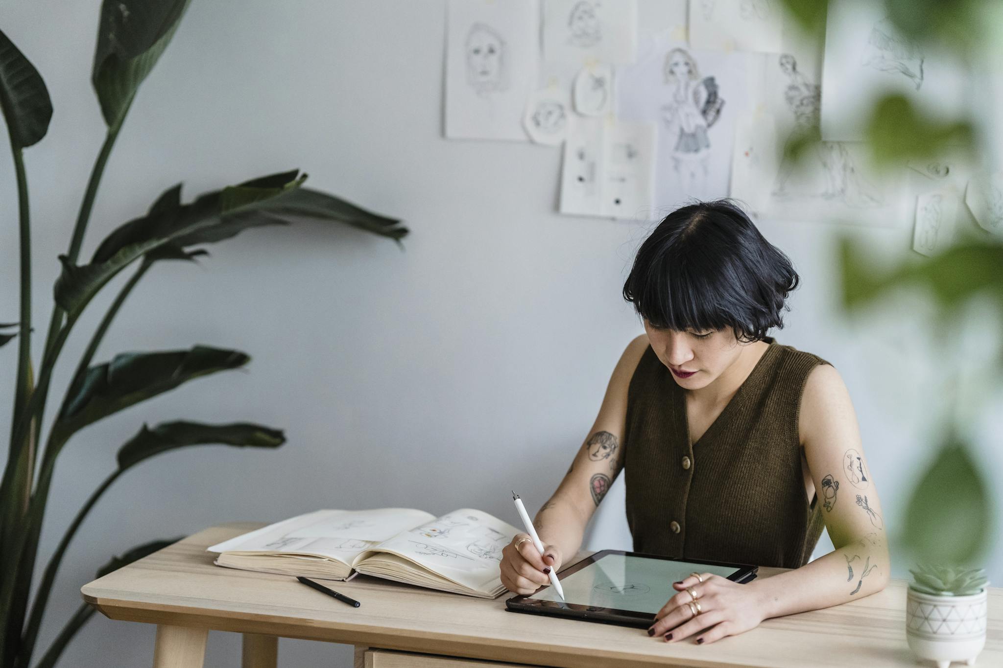 An Asian woman concentrating on digital art creation in a modern indoor workspace.